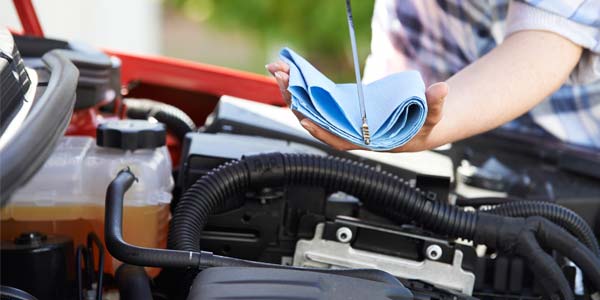 A close-up of a woman checking the oil on her car.