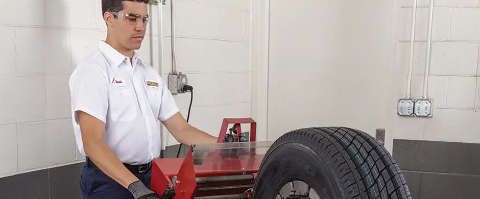 Les Schwab employee using a siping machine to sipe a tire